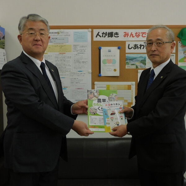 蒲生専務から教育資材を受け取る小野町の有賀仁一教育長（左）